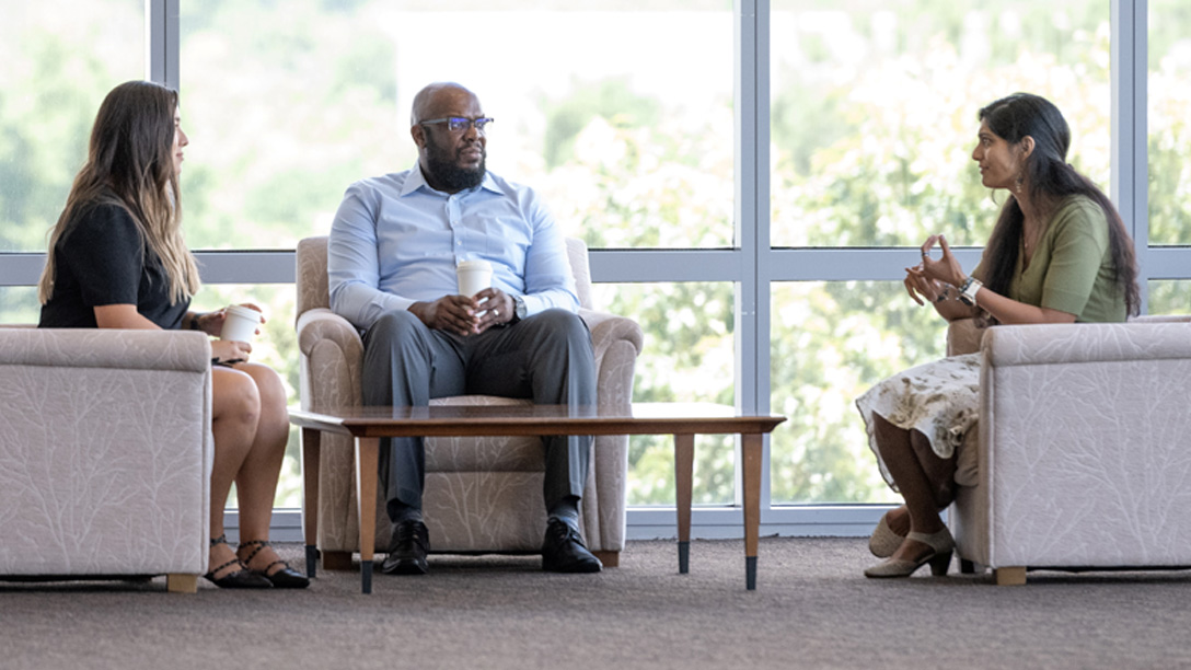 Three people sitting around a coffee table talking